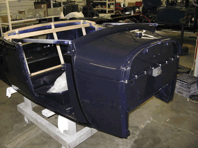 After removing the body from the rotisserie, the body wood is installed followed by the cowl and fuel tank.